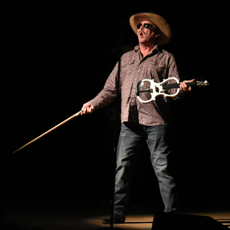 man in a hat and sunglasses playing the violin