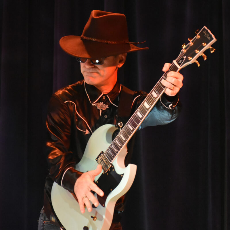 man in sunglasses and a hat playing the guitar