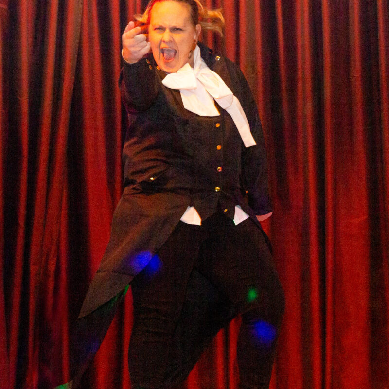 performer dressed in a quaker outfit pointing towards the crowd while singing