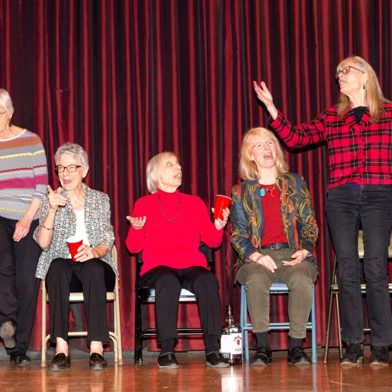 five people on a stage holding red cups