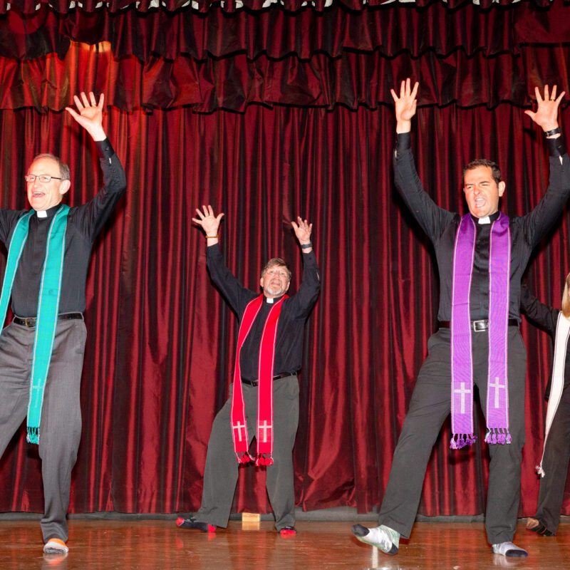 four performers dressed as catholic priests