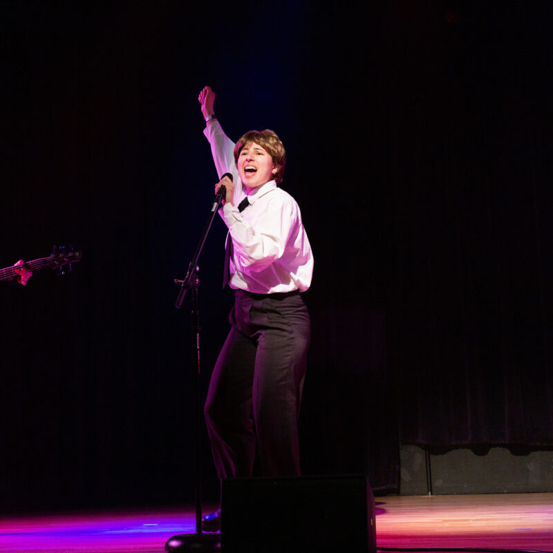 performer dressed in a formal outfit singing into a microphone