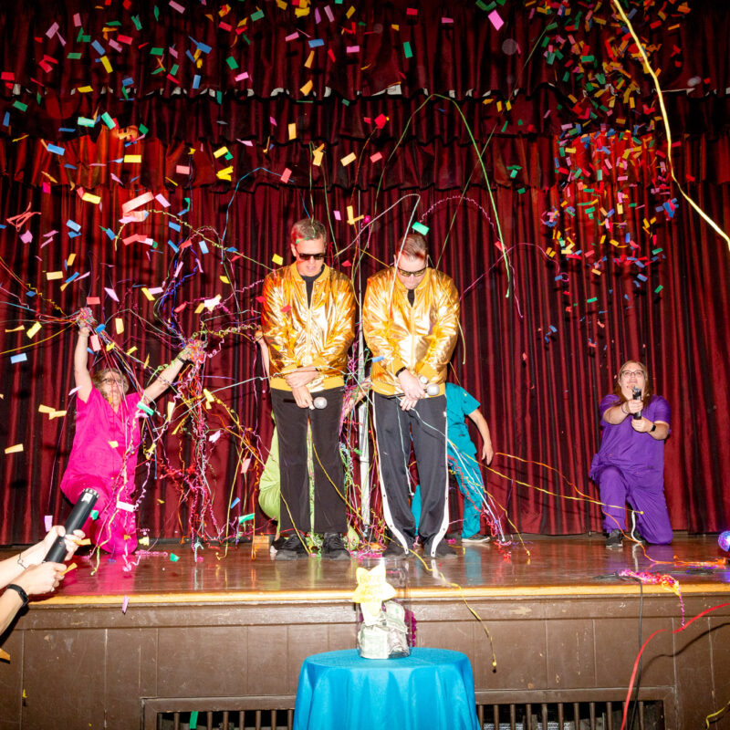 performers posing on a stage while confetti is raining down on them