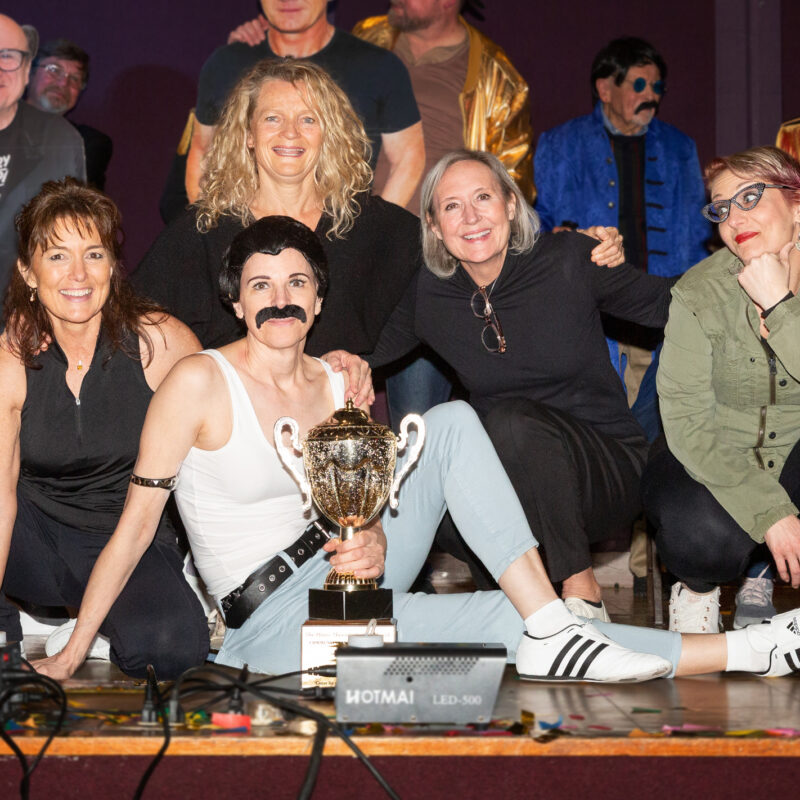 group of performers posing next to a trophy on a stage