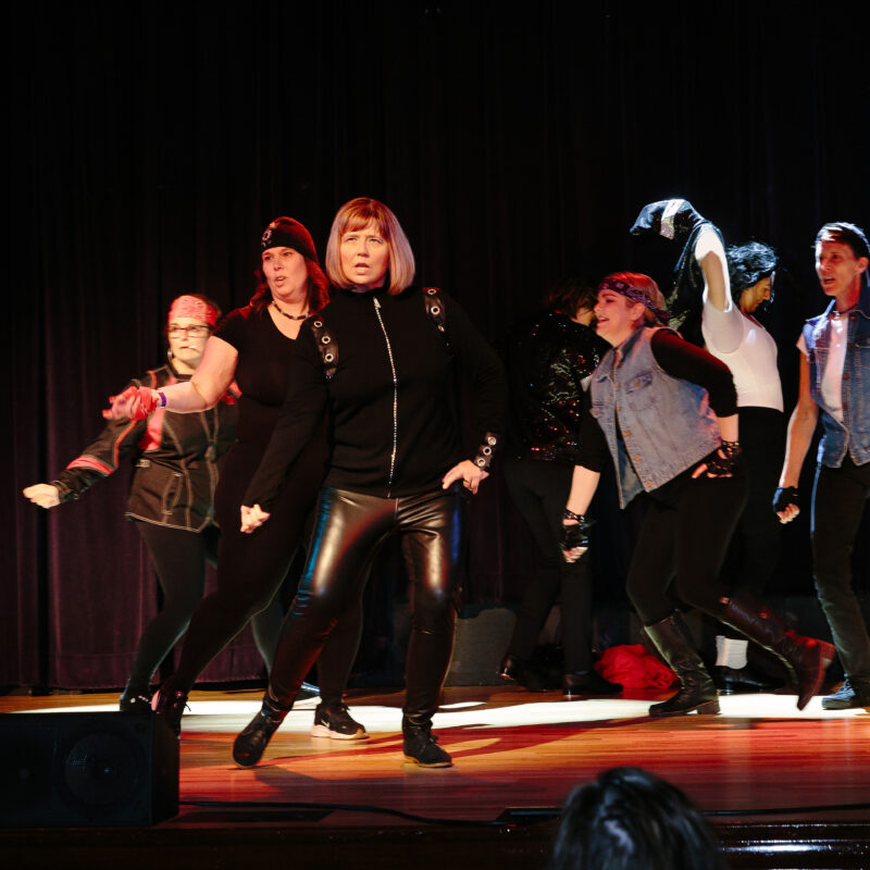 performers wearing biker themed outfits on a stage