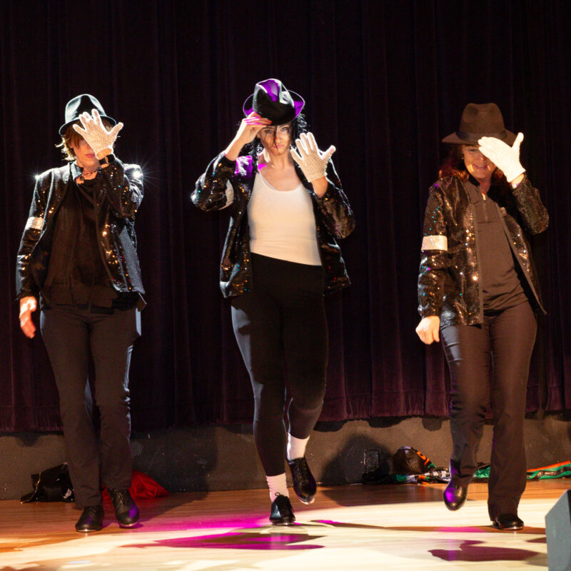 three performers wearing hats covering their faces on the stage