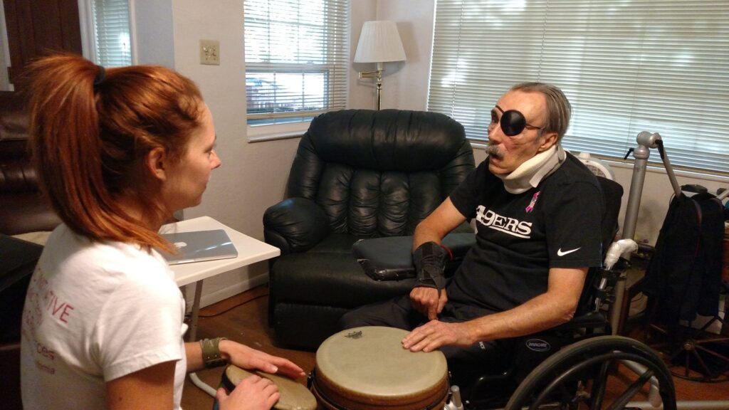 a woman assisting a man playing a drum