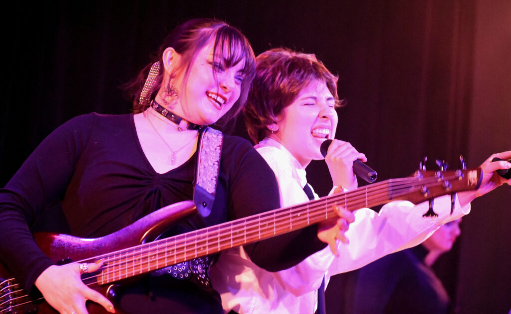 two girls playing a guitar and singing